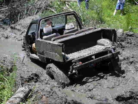 1988 Ford Bronco - Vehicle is stuck in thick mud, with only the rear visible and tires submerged.