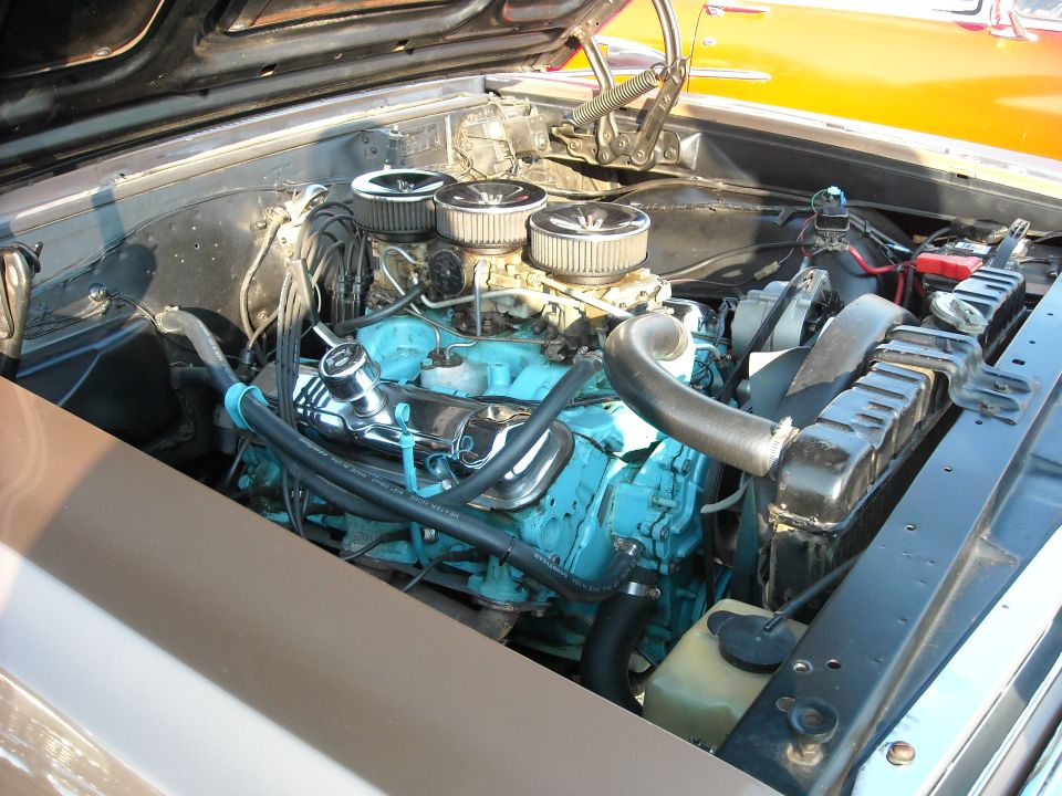 Teal-painted V8 engine with triple air cleaners in engine bay