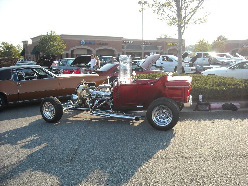 Red T-bucket hot rod with exposed chrome engine at a car show