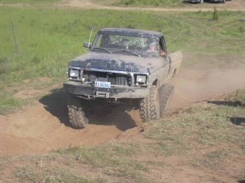 1988 Ford Bronco - This pickup truck is navigating a challenging off-road terrain, kicking up a cloud of dust.