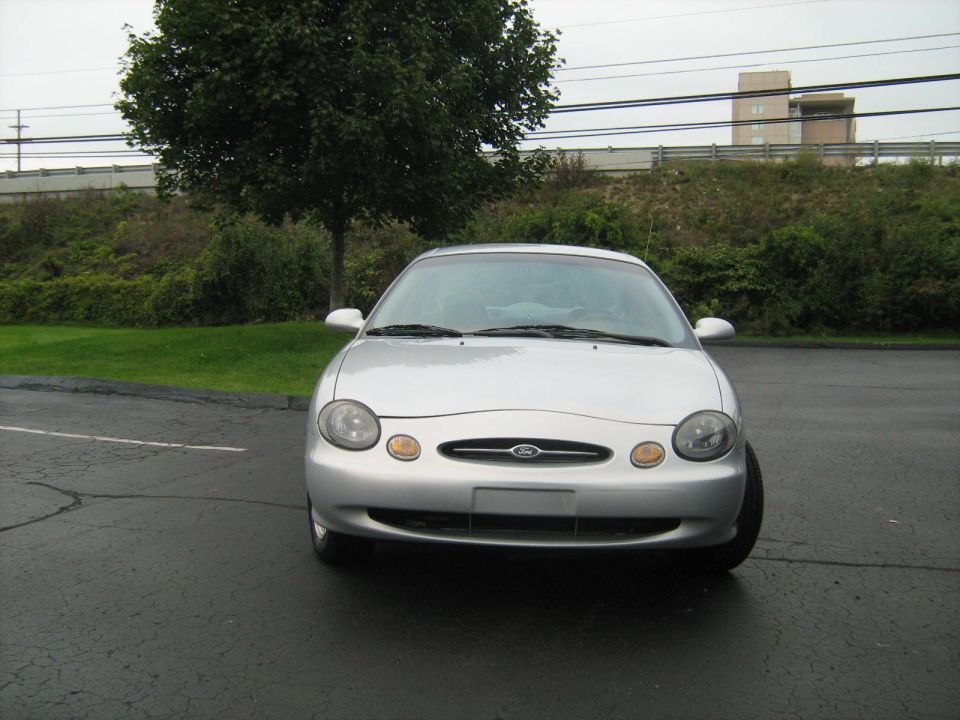 Silver Ford Taurus parked on asphalt, front view.