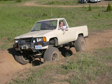 1988 Ford Bronco - This pickup truck is navigating a challenging dirt terrain, showing its off-road capabilities.