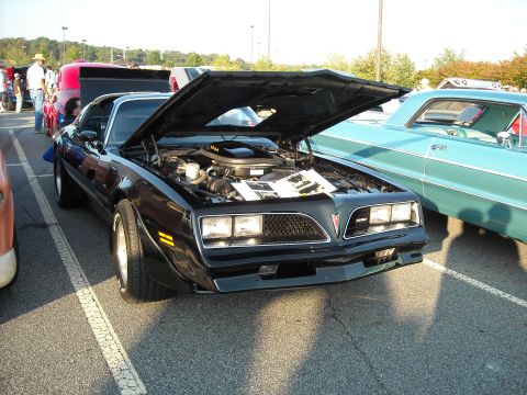1979 Ford F-150 - Front view of a black 1977 Pontiac Firebird Trans Am at a car show, hood open.