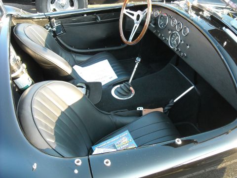 1979 Ford F-150 - The interior of a classic black sports car is visible, bucket seats and a dashboard with numerous gauges.