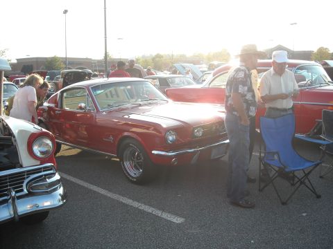 1979 Ford F-150 - A red 1965 Ford Mustang coupe is parked at a car show with people gathered around.
