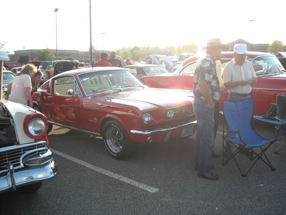 Red 1965 Ford Mustang coupe with chrome trim and aftermarket wheels