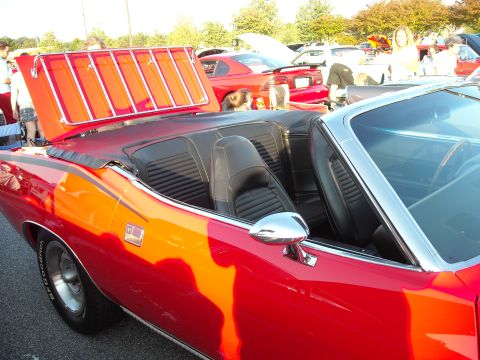 1979 Ford F-150 - A red convertible with its trunk open, revealing a luggage rack, is parked at a car show.