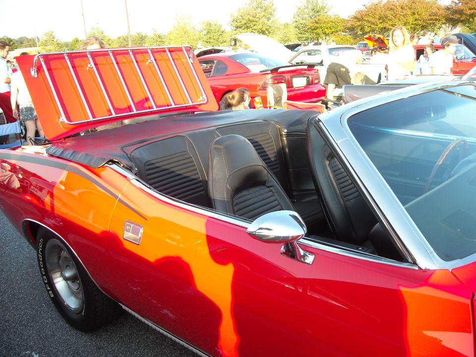Red convertible with luggage rack, black interior, and chrome accents. Seen from the side