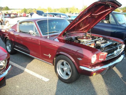 1979 Ford F-150 - A maroon 1965 Ford Mustang coupe is displayed with its hood open, revealing the engine compartment.