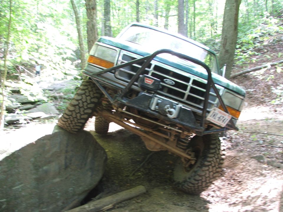 Green off-road truck with winch on rock, license plate JKL-6741