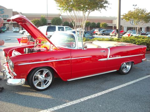 1979 Ford F-150 - A classic red convertible is parked with its hood up, revealing the engine bay.