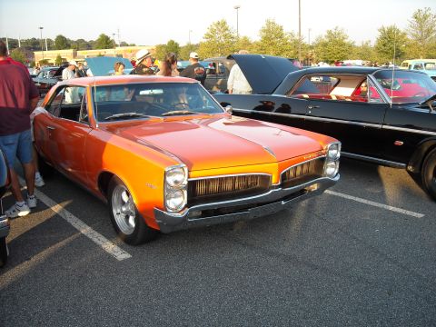 1979 Ford F-150 - An orange 1966 Pontiac Tempest coupe is parked next to a black car at an outdoor event.