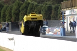 1992 Ford Mustang - A yellow car lifts its front wheels off the ground during a drag race event.