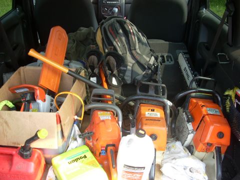 2000 Chevrolet Tahoe - Multiple chainsaws and yard equipment are packed into the cargo area of a vehicle.