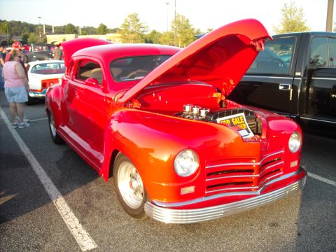 1979 Ford F-150 - A red coupe sits with its hood open, displaying its engine and a for sale sign at a car show.