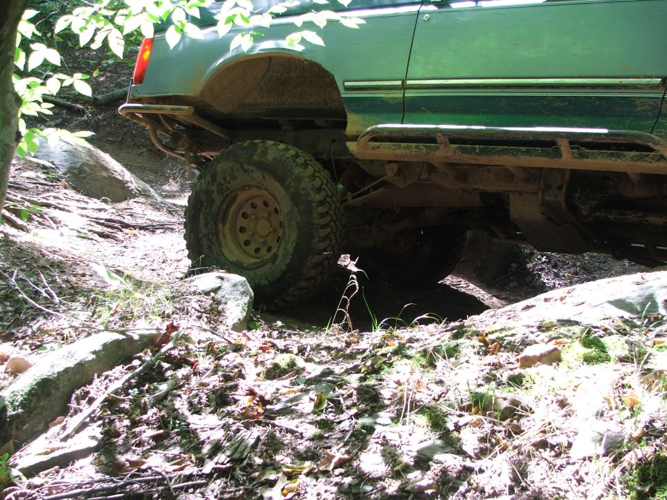 Green SUV side view, off-roading on a rocky trail