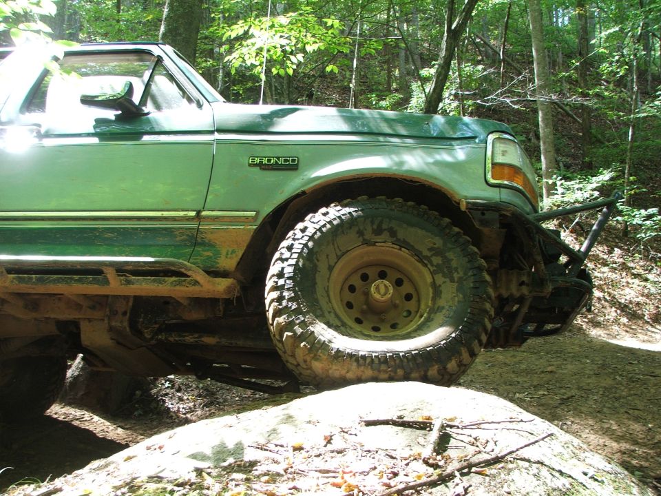 1996 Ford Bronco with aftermarket bumper and side steps on a rocky trail