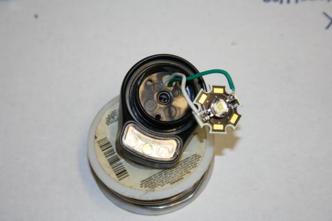 1984 Ford Bronco - A disassembled LED light assembly with its wiring connected to a black housing, resting on a spool of wire.