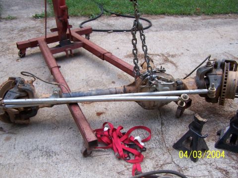 1979 Ford F-150 - An axle assembly is being worked on, suspended by a hoist with red straps and jack stands on the ground.