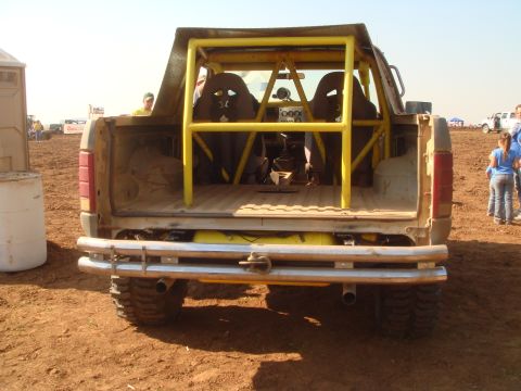 1992 Ford Bronco - Rear view of a heavily modified Ford Bronco with a roll cage and racing seats, likely from the late 1980s.