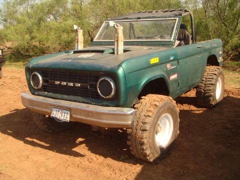 1992 Ford Bronco - This modified Ford Bronco features oversized tires, a roll cage, and prominent exhaust stacks, suggesting off-road use.