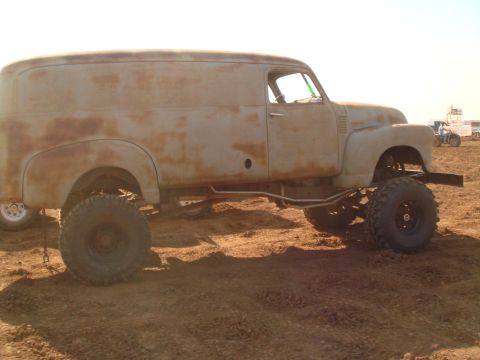 1992 Ford Bronco - Modified panel van sits high on large tires in a dirt lot.