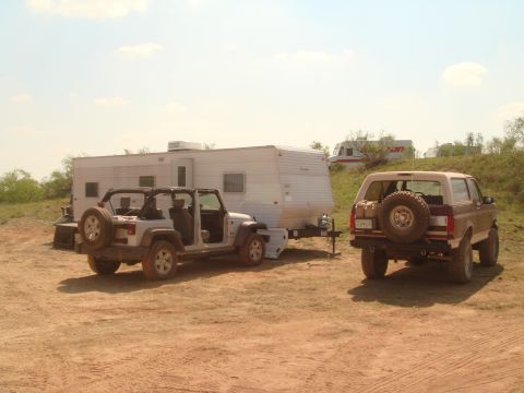 1992 Ford Bronco - A brown 1992 Ford Bronco is parked in a dirt lot next to a white Jeep and a travel trailer.
