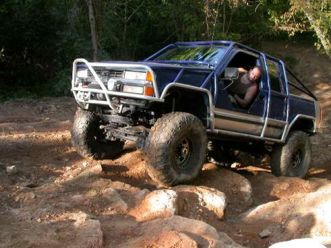 1990 Ford Bronco - Modified SUV navigates a challenging rocky trail with a driver behind the wheel.