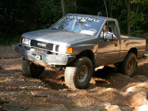 1990 Ford Bronco - This Isuzu pickup truck navigates a rough dirt trail, its off-road capabilities with a robust aftermarket bumper.