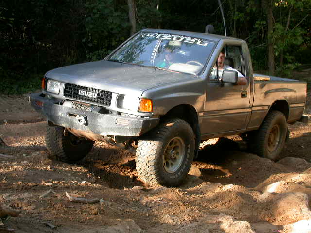 Gray Isuzu pickup truck with aftermarket bumper on a dirt trail