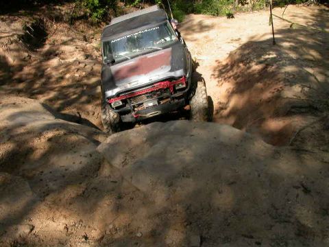 1990 Ford Bronco - This vehicle is navigating a challenging off-road course, with its front tires climbing over a large rock.