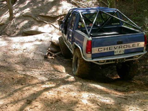 1990 Ford Bronco - This Chevrolet pickup truck navigates a challenging off-road trail with a custom roll cage.