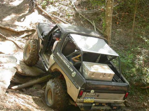 1990 Ford Bronco - This vehicle navigates a challenging rocky incline on a wooded trail.