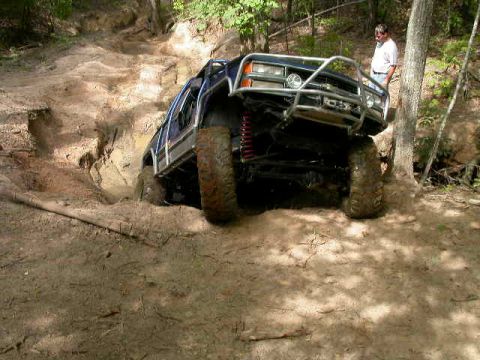 1990 Ford Bronco - An off-road SUV navigates a challenging dirt trail, demonstrating its climbing capability.
