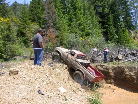 1988 Ford Bronco - Pickup truck attempts to ascend a challenging off-road obstacle.