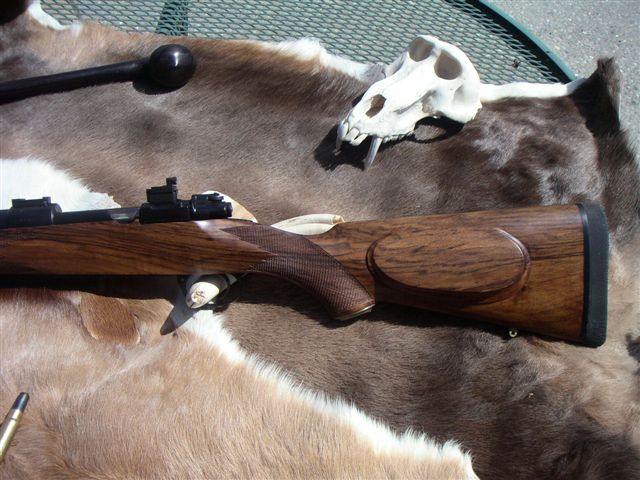 Rifle with wooden stock and scope, laid on animal hide next to a skull