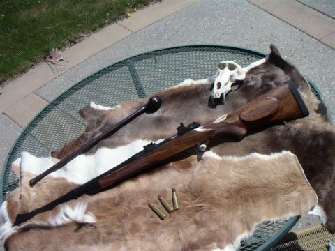 1991 Ford Bronco - A rifle, animal skull, and ammunition are arranged on animal pelts on an outdoor table.