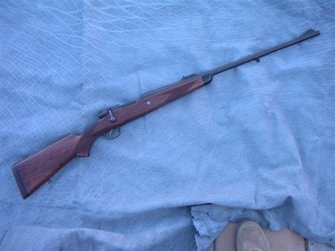 1991 Ford Bronco - Bolt-action rifle with wooden stock and metal barrel displayed on a blue tarp.