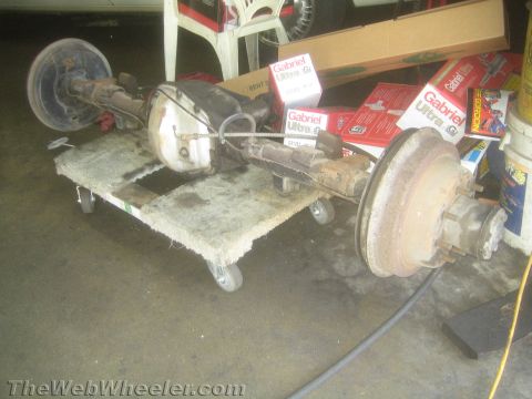 1987 Suzuki Samurai - Rear axle assembly on a dolly, with boxes of Gabriel shocks visible in the background.