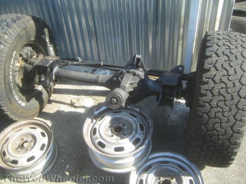 1987 Suzuki Samurai - Front axle assembly from a 1987 Suzuki Samurai, shown with spare tires and wheels.