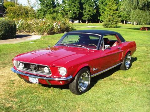 1974 Ford Ranchero - A bright red 1967 Ford Mustang coupe with a black vinyl top sits on a grassy lawn, with trees and bushes in the background.
