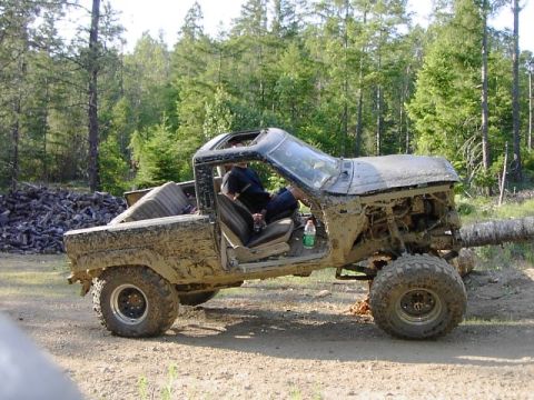 1988 Ford Bronco - This heavily muddied vehicle appears to be a Ford Bronco from the 1980s, but not specifically an 1988 model.