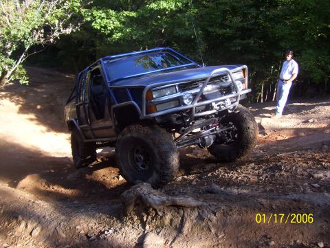 1978 Ford Bronco - A heavily modified blue SUV navigates a challenging dirt trail, its off-road capabilities.