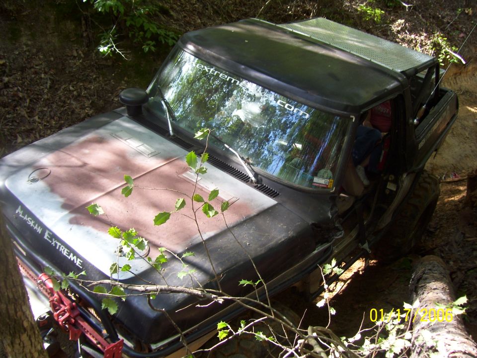 1978 Ford Bronco stuck in a dirt ditch, 'Alaskan Extreme' sticker on hood