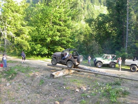 1988 Ford Bronco - Off-road vehicles are shown traversing a challenging obstacle course made of logs.