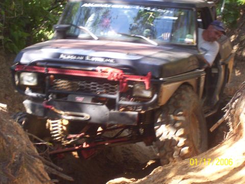 1978 Ford Bronco - 1978 Ford Bronco tackling a challenging off-road trail with a driver at the wheel.