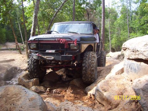 1978 Ford Bronco - Modified SUV tackles a challenging rocky trail with a driver at the wheel.