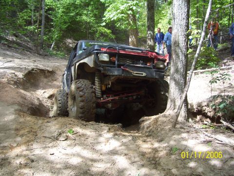 1978 Ford Bronco - This modified off-road vehicle navigates a challenging muddy terrain in a wooded area.
