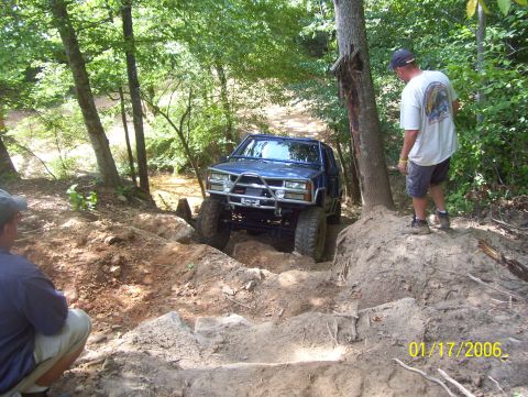 1978 Ford Bronco - A blue SUV navigates a challenging rocky trail with onlookers present.