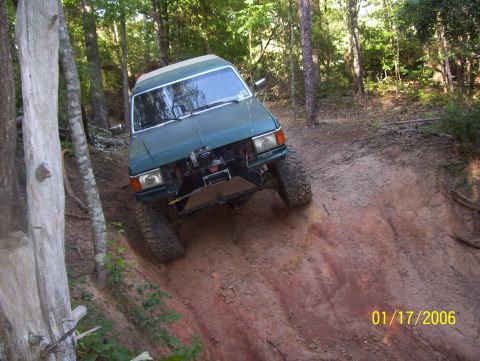 1978 Ford Bronco - This off-road vehicle navigates a steep, muddy incline surrounded by trees.